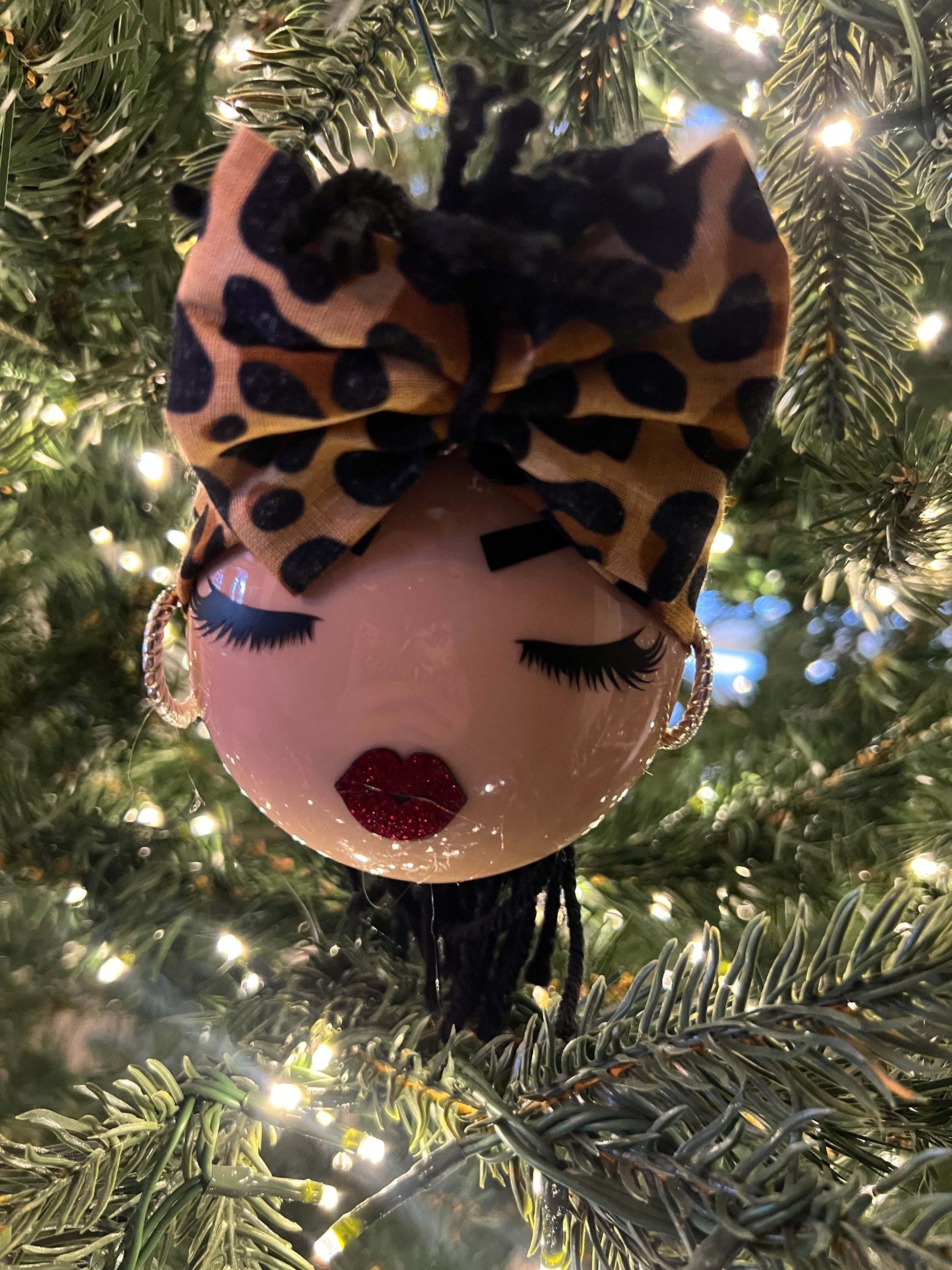Decorative ornament shaped like a face with leopard print bandana on a Christmas tree.