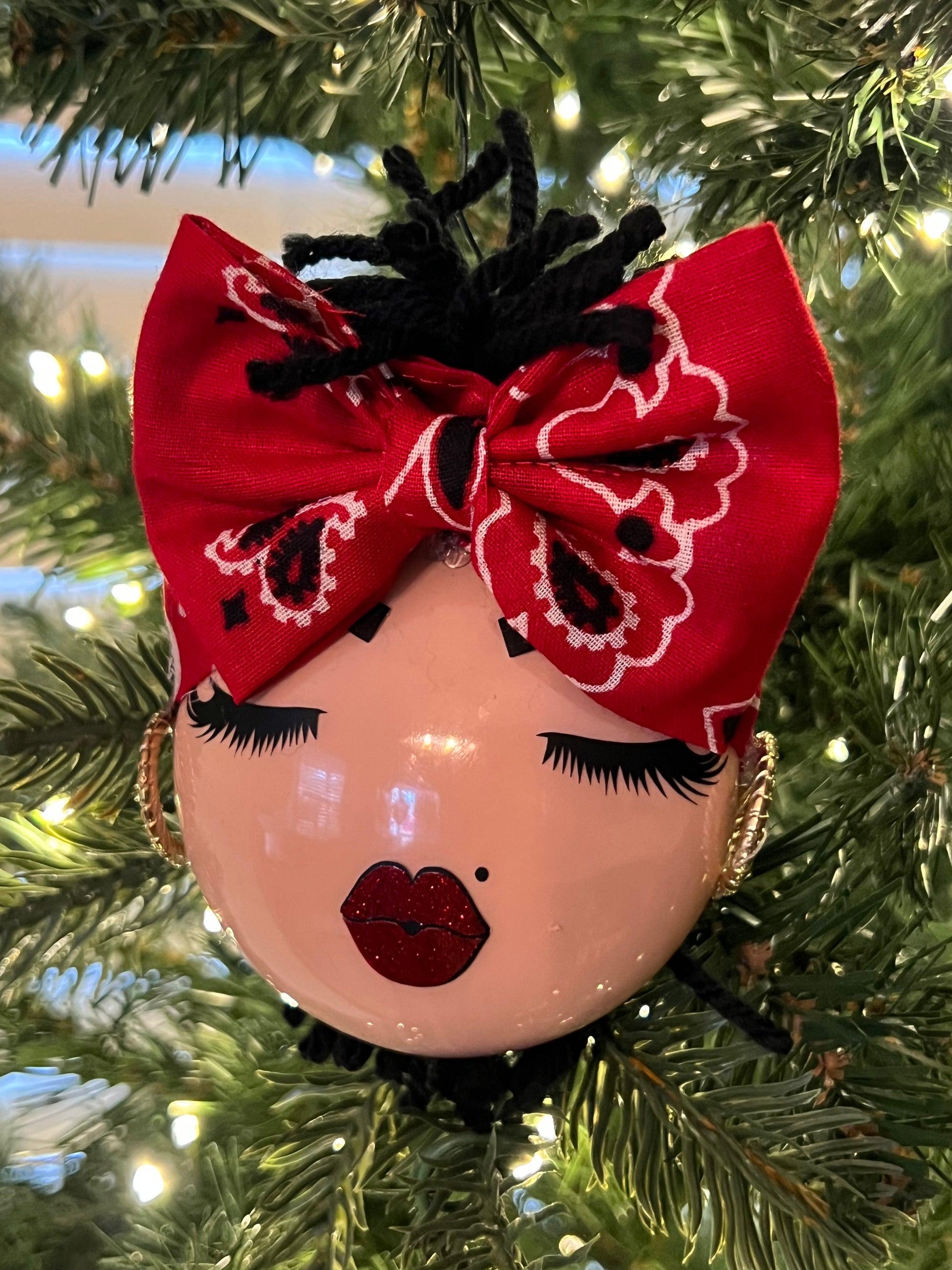 Decorative ornament with a face wearing a red bandana on a Christmas tree.
